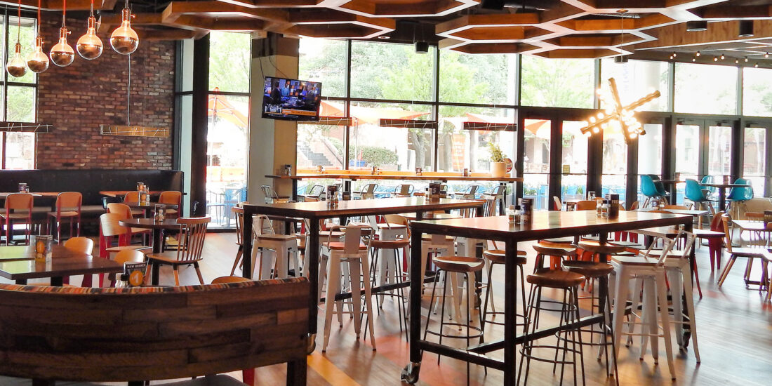 The interior of Café Express features a casual dining setup with wooden tables, comfortable seating, a hexagonal wooden grid on the ceiling, and Large windows.