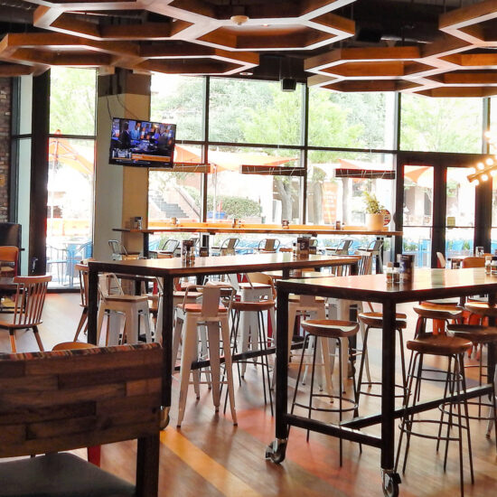 The interior of Café Express features a casual dining setup with wooden tables, comfortable seating, a hexagonal wooden grid on the ceiling, and Large windows.
