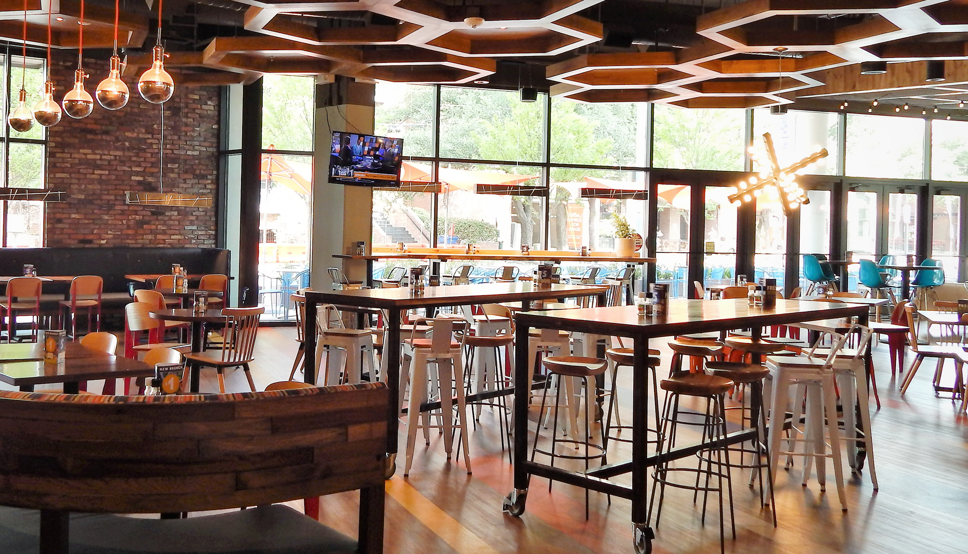 The interior of Café Express features a casual dining setup with wooden tables, comfortable seating, a hexagonal wooden grid on the ceiling, and Large windows.