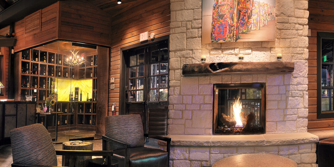 The lobby of The Ranch restaurant features rustic architecture with a limestone stone fireplace, wood accents, and warm outdoor lighting, creating a welcoming entrance.